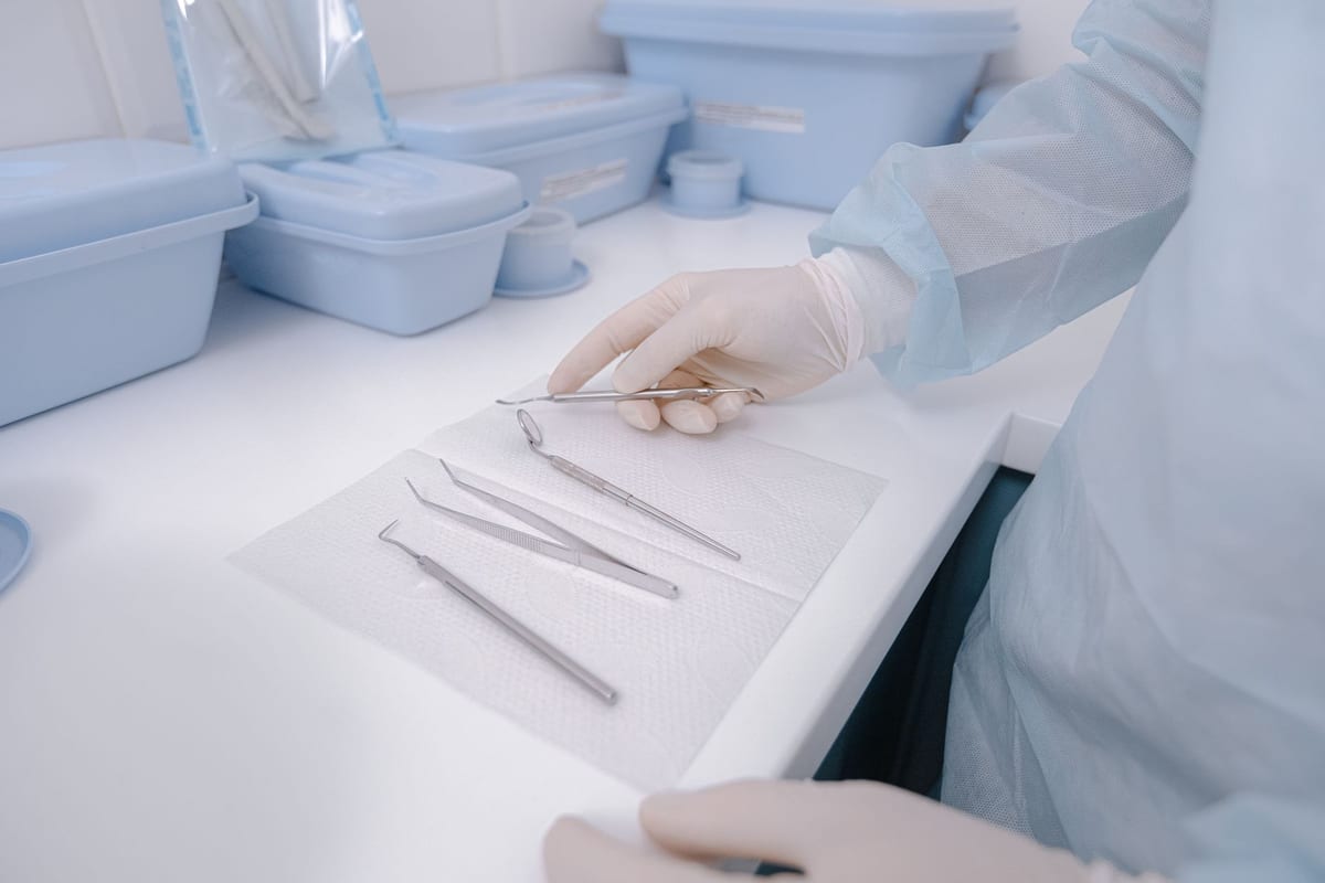 Gloved hands laying a mirror, probe and tweezers onto a fresh tray liner