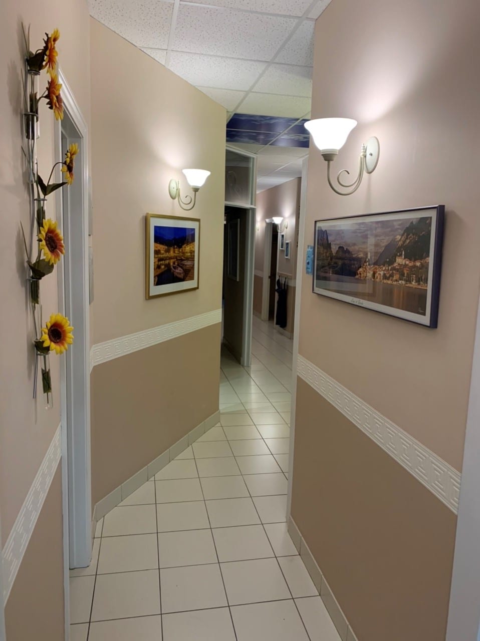 The hallway at Dr. Pat Martino & Associates, with sconces, framed prints and a sunflower display